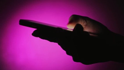 Wall Mural - Female thumbs touching and scrolling a smartphone screen in arty violet studio