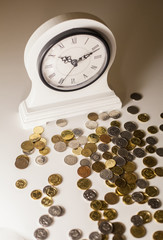 White desk clock on a white background near scattered coins or 