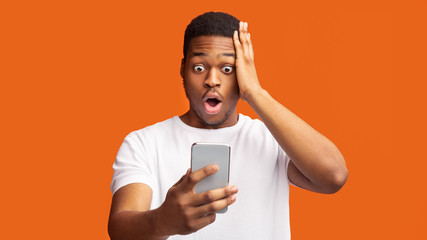 Afraid african guy looking at phone reading terrible news