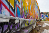 Fototapeta Młodzieżowe - Lots of colorful graffiti on a wooden wall and a crash barrier