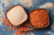 Red lentil flour in wooden bowl on gray background. Top view