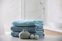 Stack Of Fresh Towels, Soap Dispenser And Bath Bombs On Table Indoors