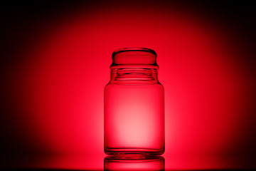 Empty glass jar on a red and black background