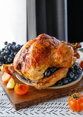 Wall Mural - Roasted whole turkey on a table with persimmon, blue grape and lemon for family Thanksgiving Holiday.