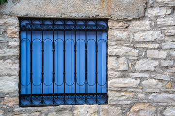 Blue wooden vintage window with a metal safety frame on a brick wall