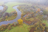 Fototapeta Krajobraz - Forest in autumn colors. Colored trees and a meandering blue river. Red, yellow, orange, green deciduous trees in fall. Peetri river, Estonia, Europe