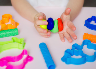 child hands playing with colorful clay. homemade plastiline. plasticine. play dough. girl molding mo