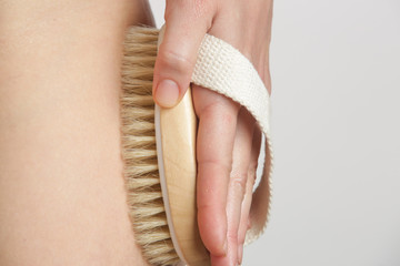 Dry body brush, Woman dry brushing body to reduce cellulite, detoxify the lymphatic system, and achieve beautiful smooth skin. Dry skin brushing as part of morning health and energy routine.