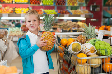 Blonde little boy holding fresh pineapple