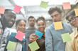 © Svitlana - Creative team at work. Group of young and positive coworkers putting colorful sticky notes on a glass window while standing in the modern office