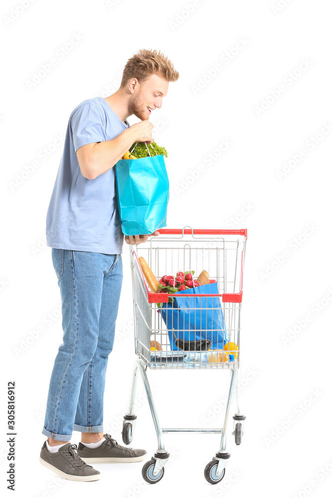 Young man with shopping cart on white background