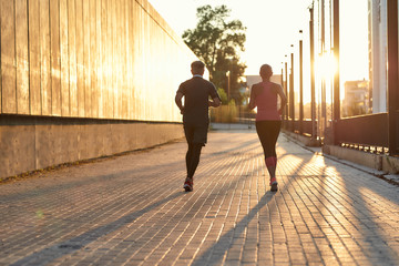 Wall Mural - Morning workout. Full length of a couple in sport clothing running together through the city street. Fitness couple