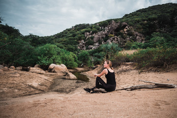 Wall Mural - Young sporty skinny girl sitting on the beach and relaxing, sand and fresh green grass around