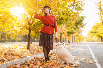 Canvas Print - Young woman walking with dog in autumn park