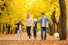 Happy Family Walking In Autumn Park