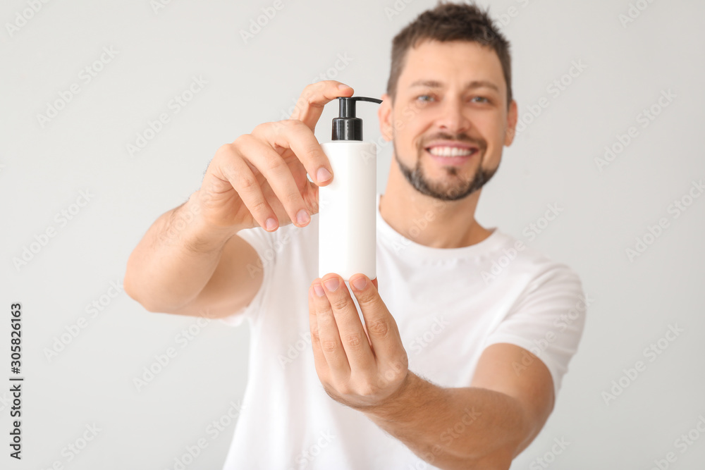 Handsome man with cosmetic product on white background