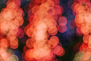 Wall Mural - Orange and red Christmas light shiny abstract round bokeh on black background. Colourful Glitter bokeh from blurry decoration bulbs.