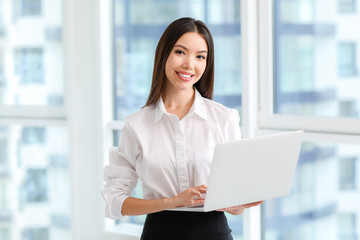 Beautiful Asian businesswoman with laptop in office