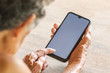 © Golden House Images - Old woman holding smart phone for shpping online