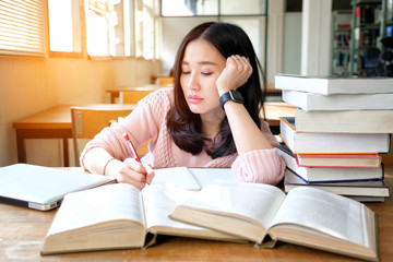 Young woman studying in a library and thinking of something