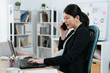 © PR Image Factory - Pregnant businesswoman at work in day time. Cheerful asian chinese office lady in maternity talking on mobile phone while sitting at modern workplace. elegant future mother worker in suit use laptop