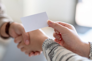 Wall Mural - Two people shaking hands and exchanging empty business card