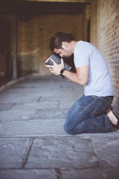 Vertical shot of a male on his knees on the ground with the bible against his head praying