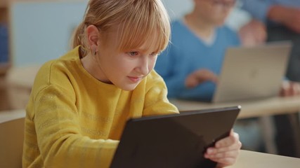 Poster - Elementary School Computer Science Class: Cute Girl Uses Digital Tablet Computer, Her Classmates work with Laptops too. Children Getting Modern Education in STEM, Playing and Learning