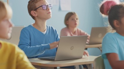 Poster - Elementary School Computer Science Class: Smart Boy Uses Laptop Computer, His Classmates work with Laptops, Everybody Listens Attentively to the Teacher. Children Getting Modern Education