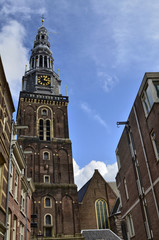 Wall Mural - Amsterdam, Holland. August 2019. The bell tower of the old church stands out in height on the houses making itself noticed from afar.