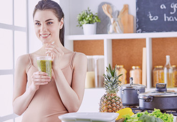 Wall Mural - a young girl drinks a cocktail on a kitchen