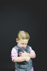 Wall Mural - Vertical shot of a child holding the bible against his chest wit ha black background