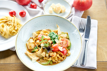 Italian pasta with seafood and tomato sauce. Pasta Gamberini. Close-up tagliatelle wind it around a fork with a spoon. Parmesan cheese