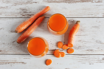 Wall Mural - Carrot juice in a glass and fresh carrots on a table. Healthy dieting drink in a glass on wooden table background.