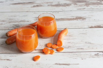 Wall Mural - Carrot juice in a glass and fresh carrots on a table. Healthy dieting drink in a glass on wooden table background.