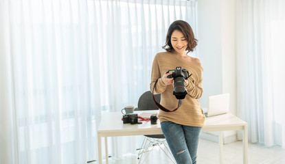 Portrait of beautiful asian photographer woman working in office holding camera with laptop. Business people employee freelance online marketing.  Freelance girl creative startup business concept