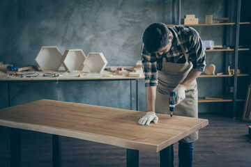 Photo of handsome careful guy assembling handmade slab table making finish actions before selling website own wooden business industry woodwork shop garage indoors