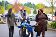 Disabled boy in wheelchair in city  with family and caregiver