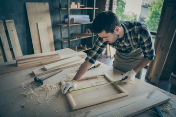 Wall Mural - Photo of focused serious man concentrated on measuring length of wooden frame correctly by using tape line