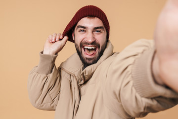 Canvas Print - Image of man in winter jacket and hat smiling while taking selfie photo