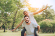 © sakarin14 - Romantic caucasian couple lover funny joy freedom. Man man holds woman on shoulders back in park, Romancetic and Love concept.