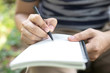 © methaphum - close up hand young man are sitting using pen writing Record Lecture notepad into the book in the parks.