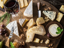 Cheese Platter With Organic Cheeses, Fruits, Nuts And Wine On Wooden Background. Top View. Tasty Cheese Starter.