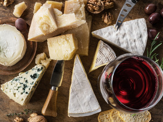 Wall Mural - Cheese platter with organic cheeses, fruits, nuts and wine. Top view. Tasty cheese starter.