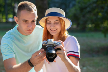 Wall Mural - Young teenage couple taking pictures of one another outdoors in sunny summer park.