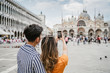 Loving couple in Venice, Italy - Millennials take a photo in the Piazza San Marco with the smartphone - Asian young people on vacation in Italy