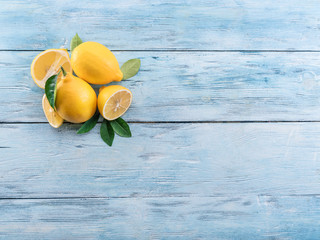 Wall Mural - Ripe lemons and lemon leaves on blue wooden background. Top view.