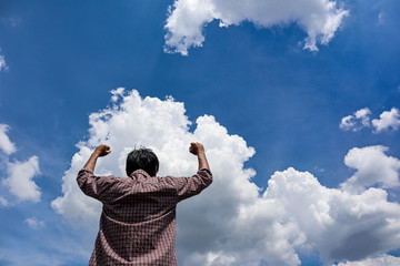 Wall Mural - A man looking into the blue sky with white cloud   holding arms up