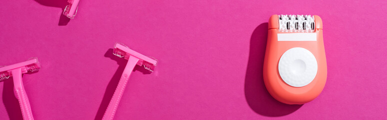 Wall Mural - top view of disposable razors, epilator on pink background, panoramic shot