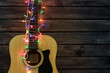 © Nikolay - Acoustic guitar in a New Year's garland, guitar in a garland under a wooden wall, copy spaсe